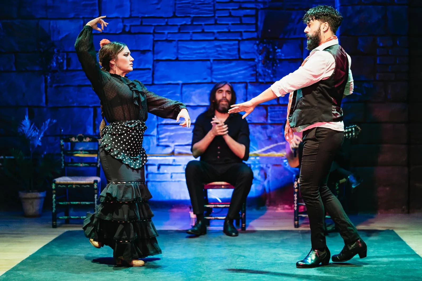 Pareja de baile con bata de cola negra actuando juntos en el escenario de Baraka Sala Flamenca.
