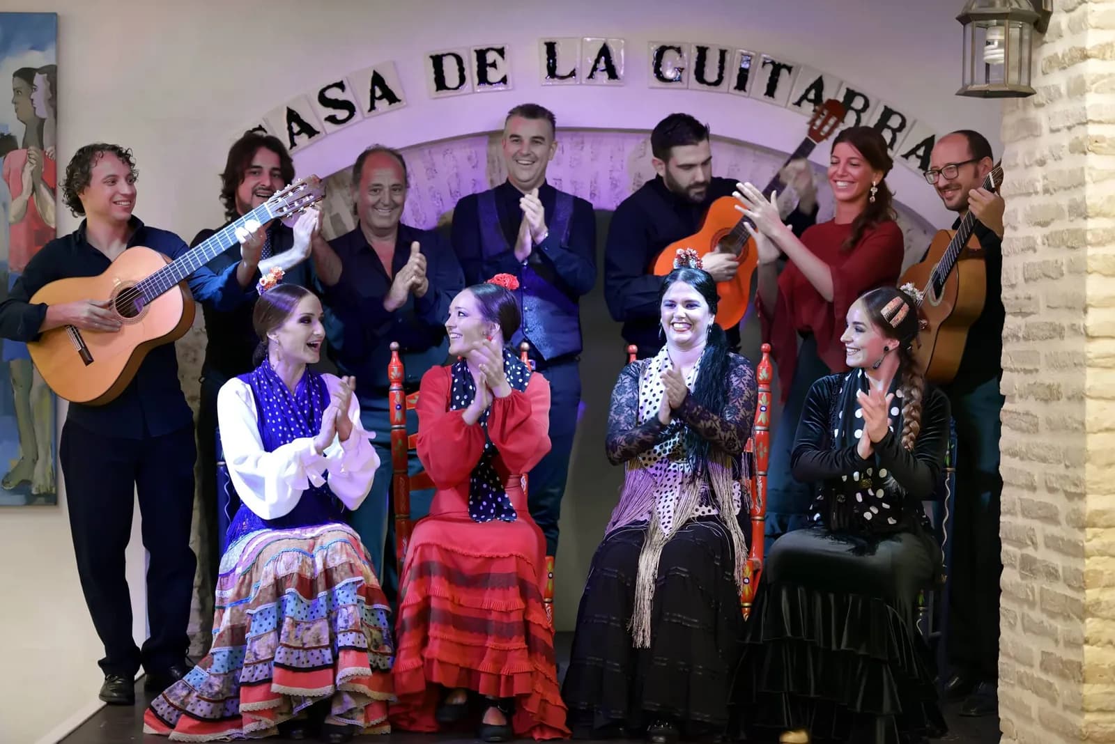 Grupo de artistas de Casa de la Guitarra posando en el escenario bajo el rotulo CASA DE LA GUITARRA, con bailaoras, guitarristas y cantaores.