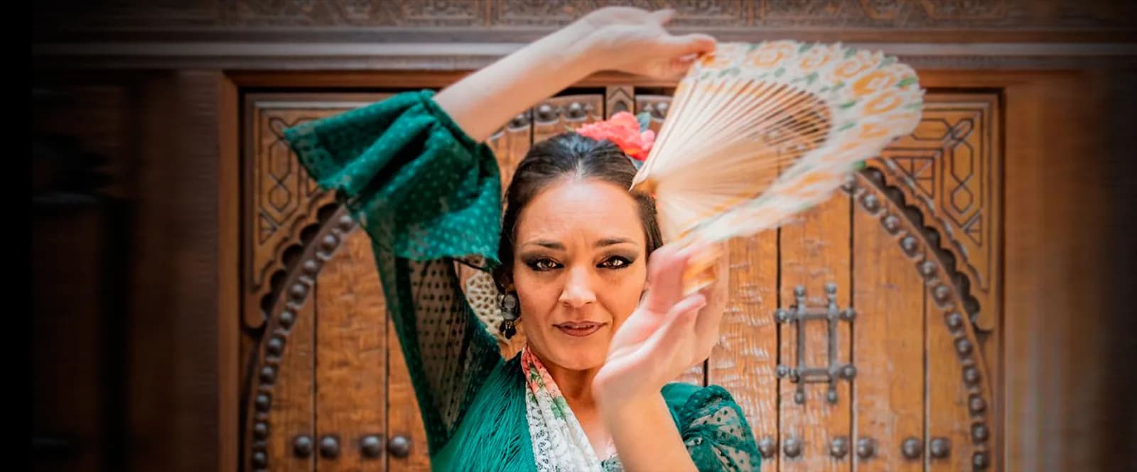 Bailaora con abanico y vestido verde bailando ante una celosia arabe en Casa de la Memoria.