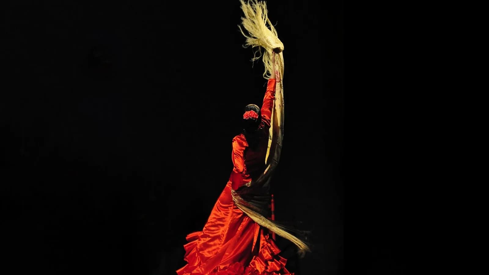 Bailaora con falda roja de volantes en movimiento sobre fondo negro en Casa Duende.