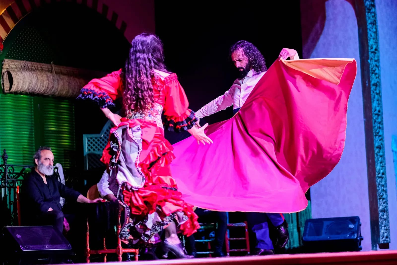 Bailaora con vestido rosa de gran cola bailando junto a un bailaor en la adaptacion flamenca de Carmen en El Palacio Andaluz.
