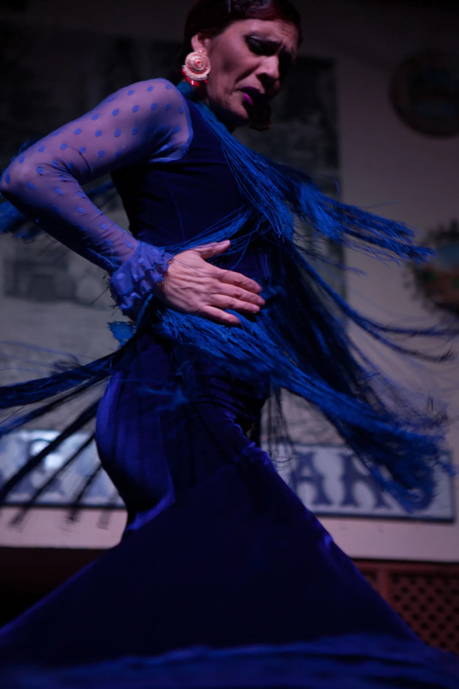 Bailaor con capa azul en pleno giro sobre el escenario de El Patio Sevillano.