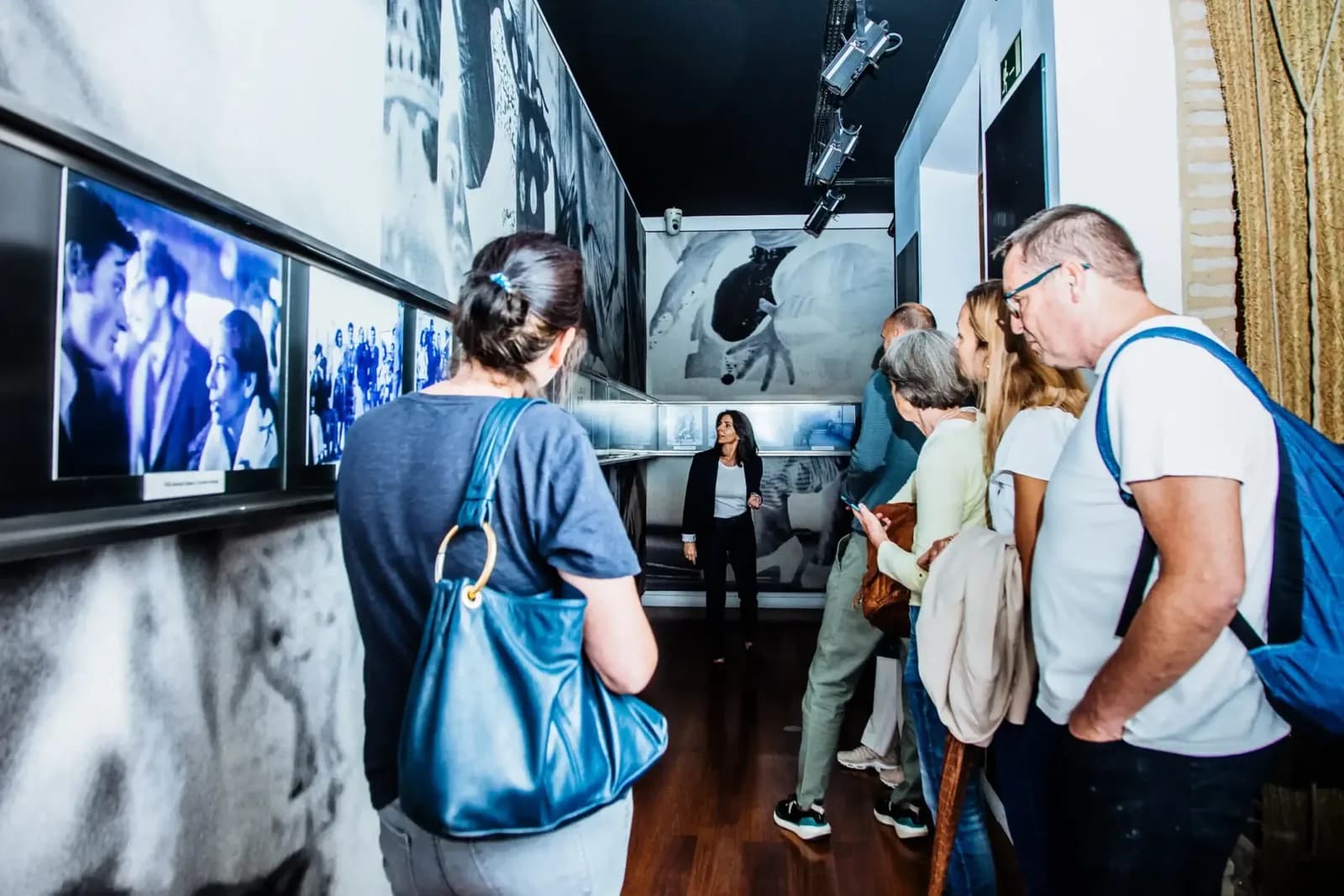 Visitantes observando pantallas con proyecciones de baile flamenco dentro del Museo del Baile Flamenco.