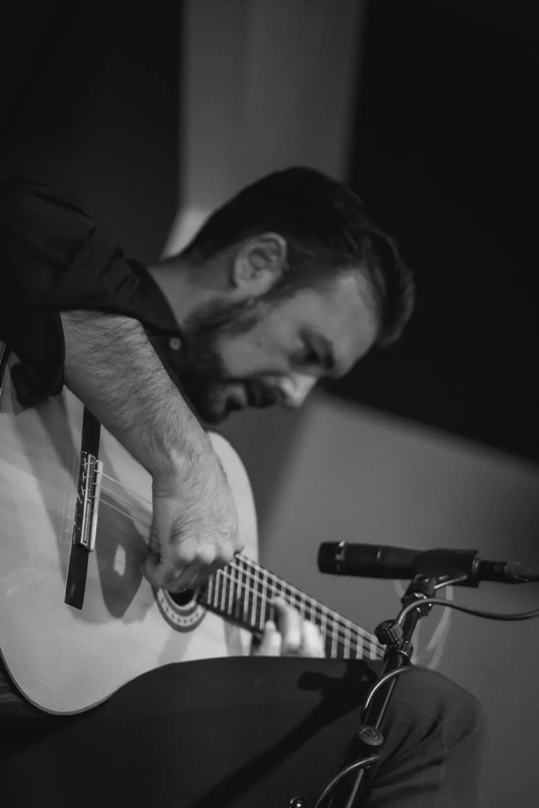 Guitarrista tocando con microfono en el escenario de Orillas de Triana, fotografia en blanco y negro.