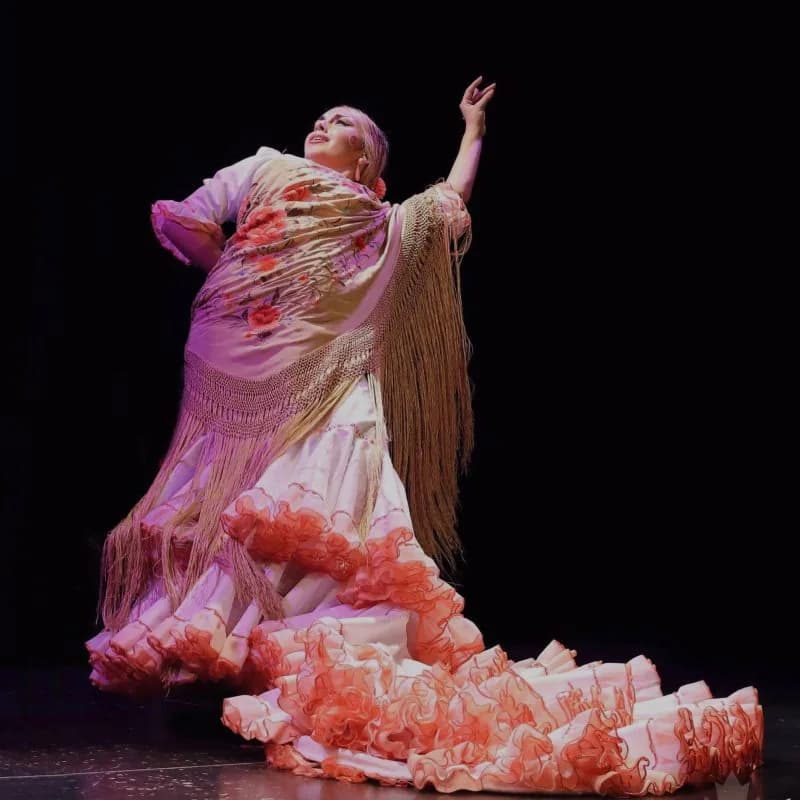 Bailaora con vestido salmon de flecos inclinada hacia atras en pleno baile sobre el escenario de La Cantaora.